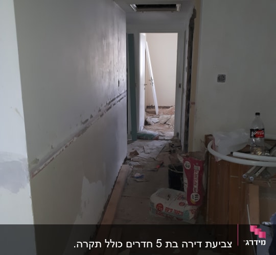 מסדרון עם קיר צבוע חלקית, שקי חומרי בניין